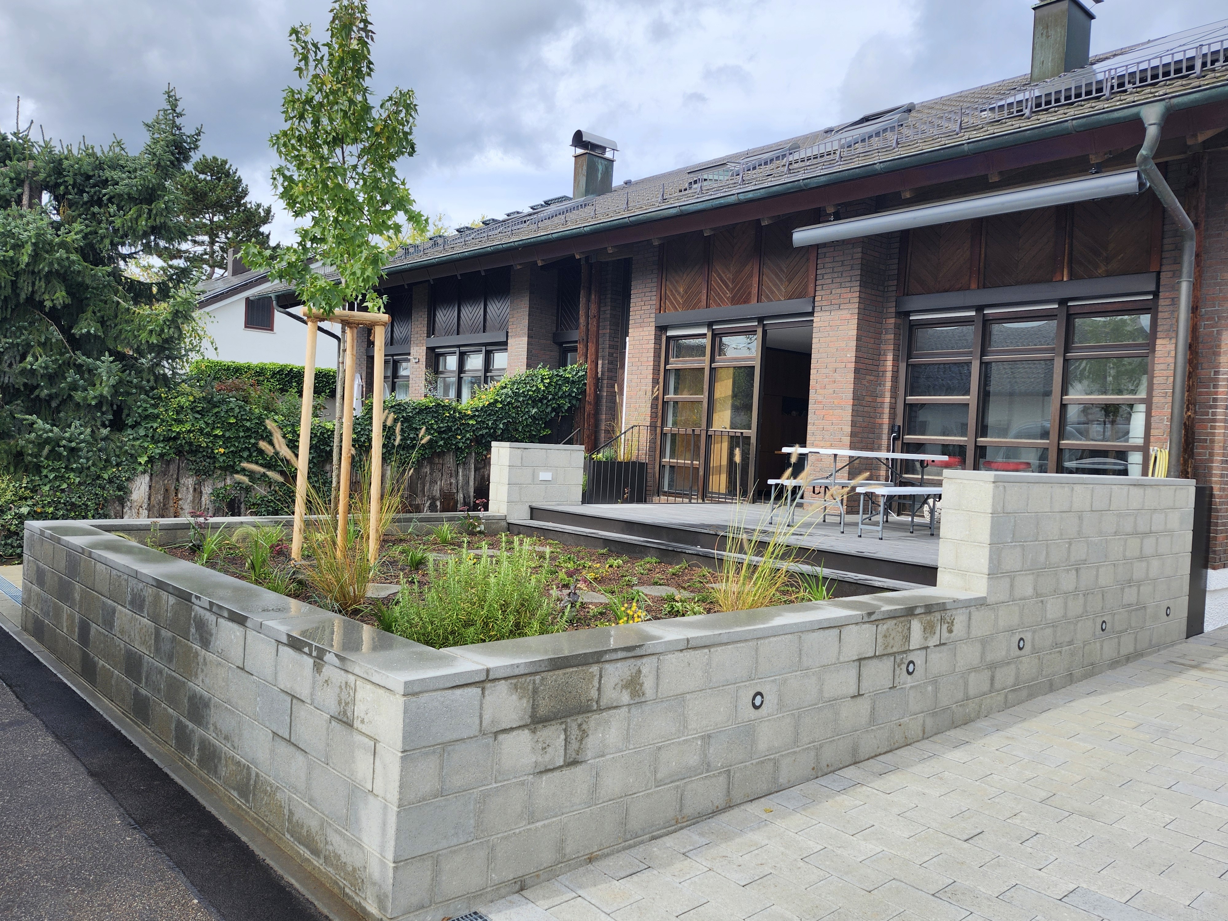 Gartenanlage mit Sitzmauer und Bepflanzung vor einem Haus, erstellt von Marohn & Binder im Gartenbau. , Marohn & Binder Gartenbau