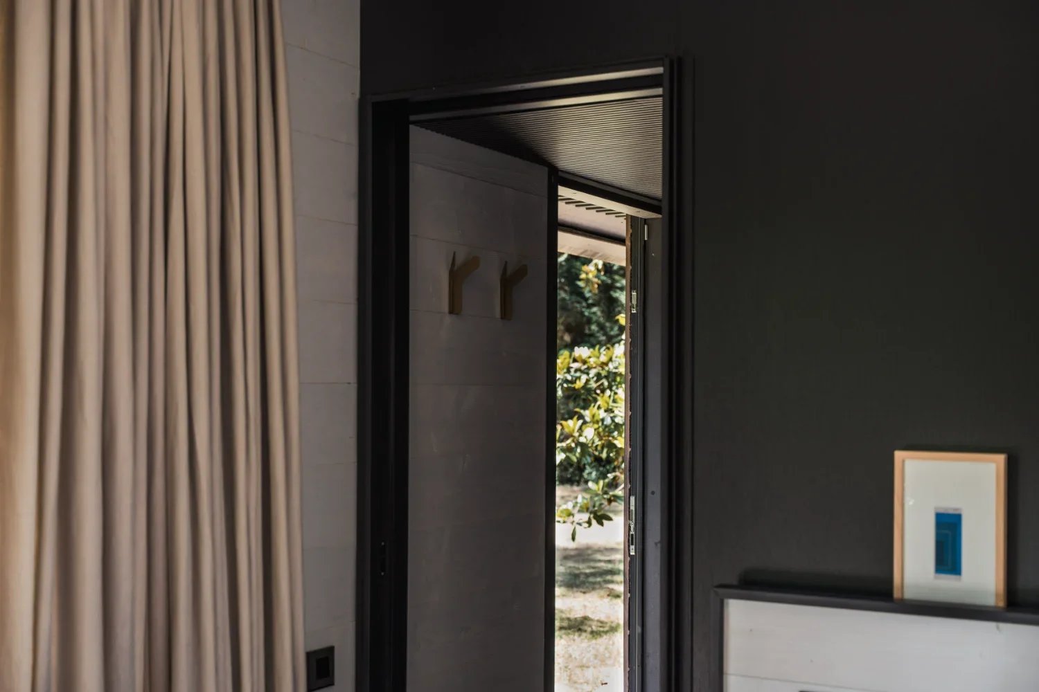 Entrée du Teshima Bourgogne, porte ouverte sur le jardin, mur noir et rideaux lin