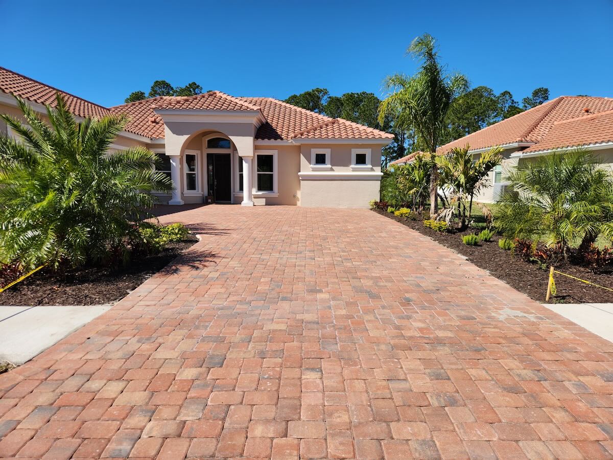 Before paver sealing - faded driveway with weeds in Daytona Beach FL