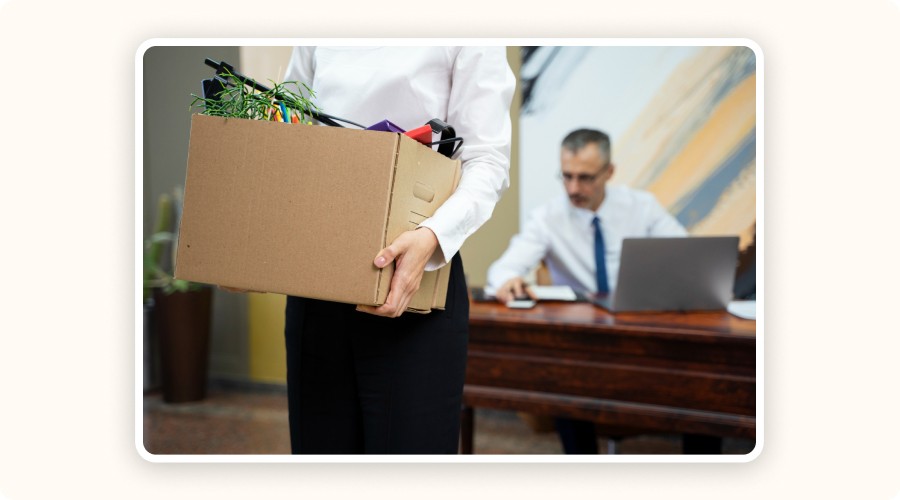 Person leaving their desk with a box of goods, representing the impact of poorly managed returns in ecommerce.