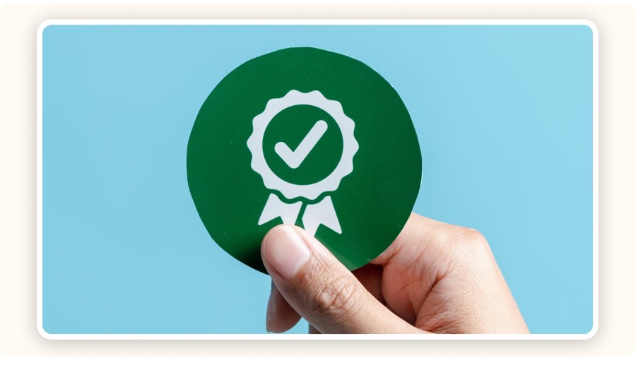 Main tenant un badge vert avec une icône de certification qualité