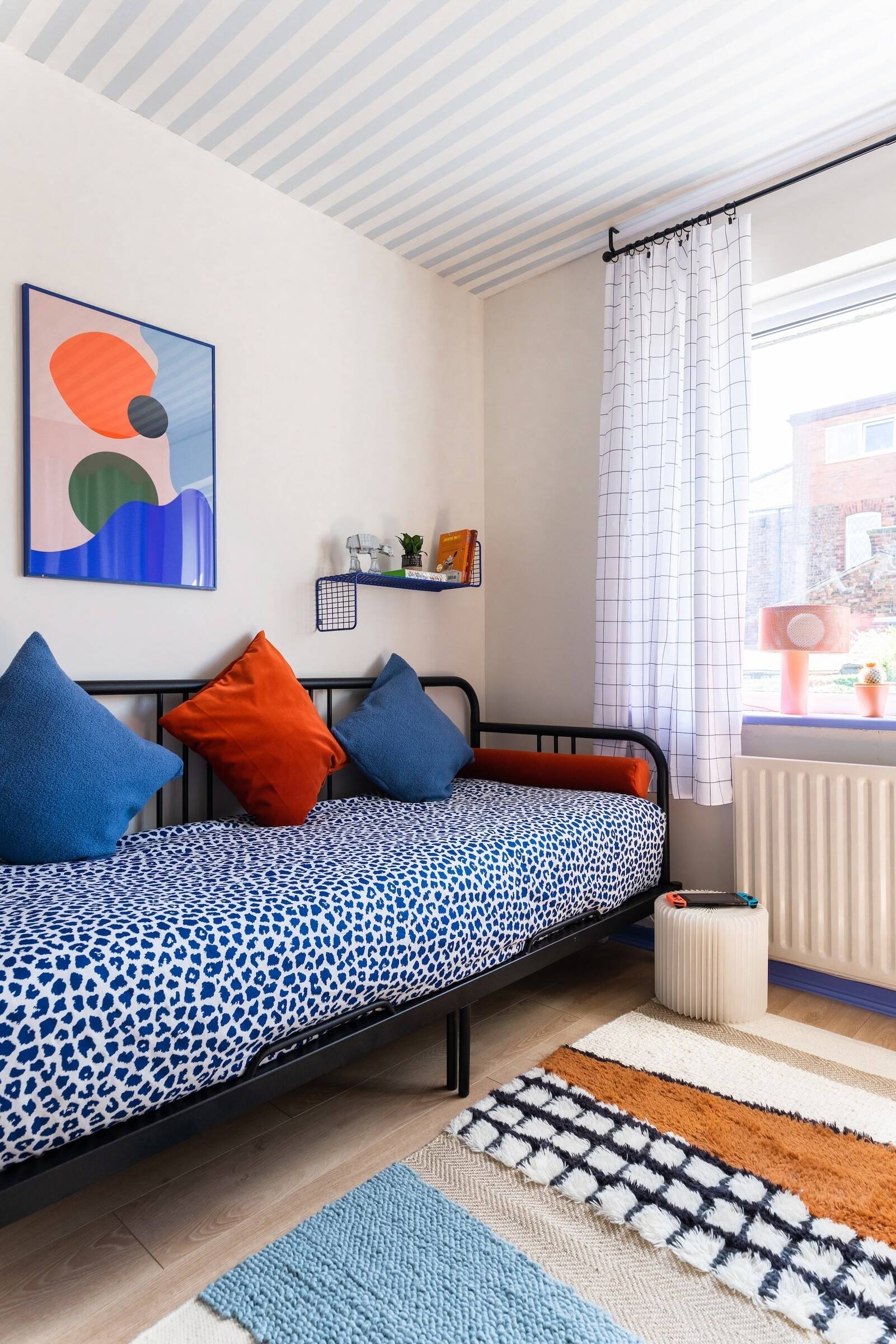 Colourful teen bedroom with cosmic theme, vibrant blue and red walls, striped ceiling wallpaper, cohesive playful colour palette, Atelier Akuko