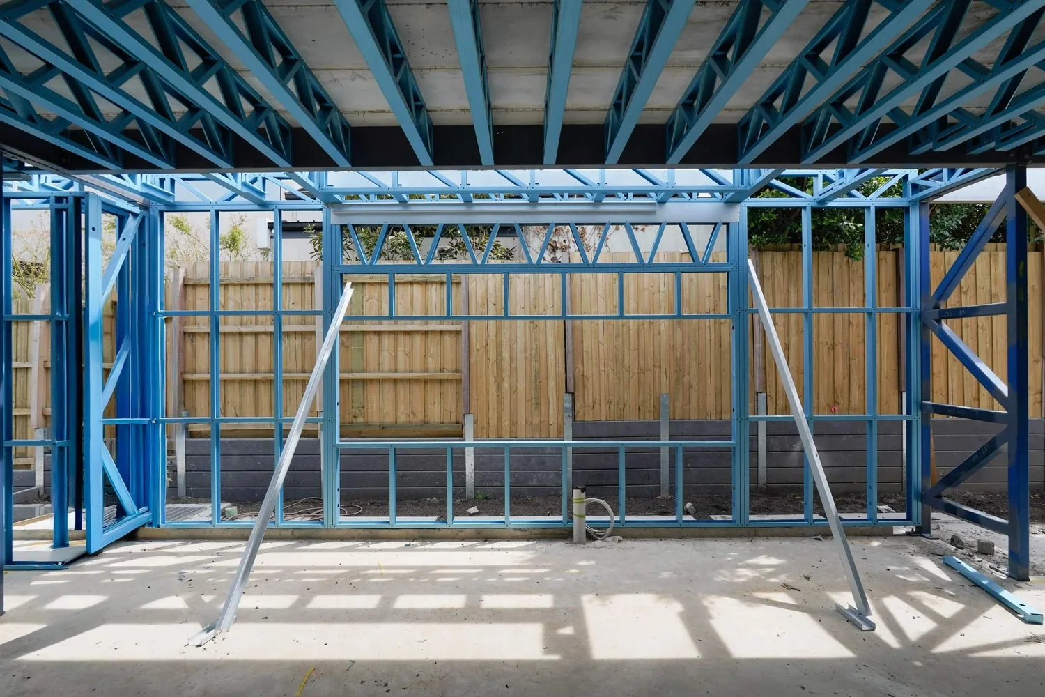 Construction site with steel frame structure and wooden fence background.