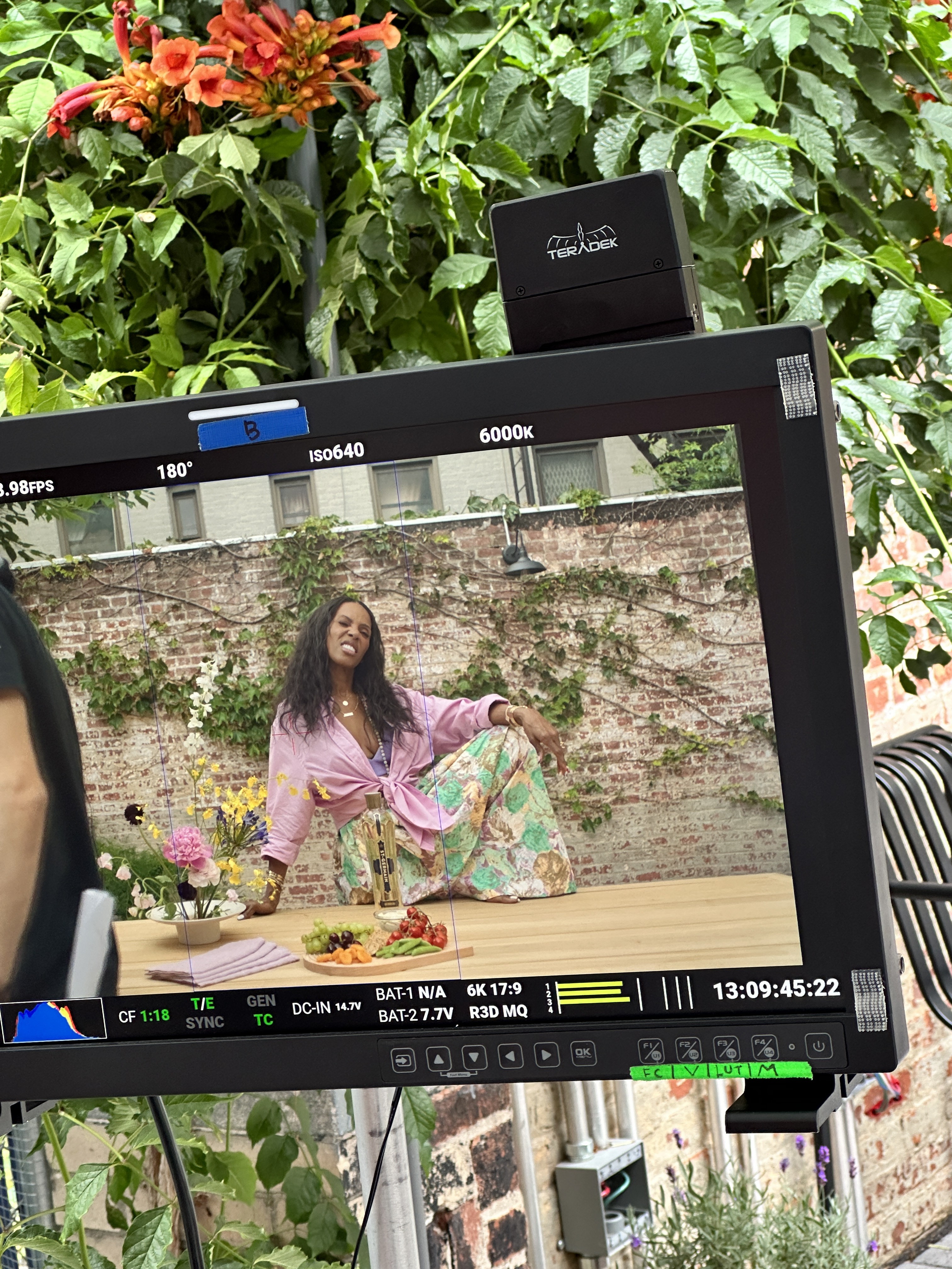 Behind the scenes camera monitor showing June Ambrose at the table