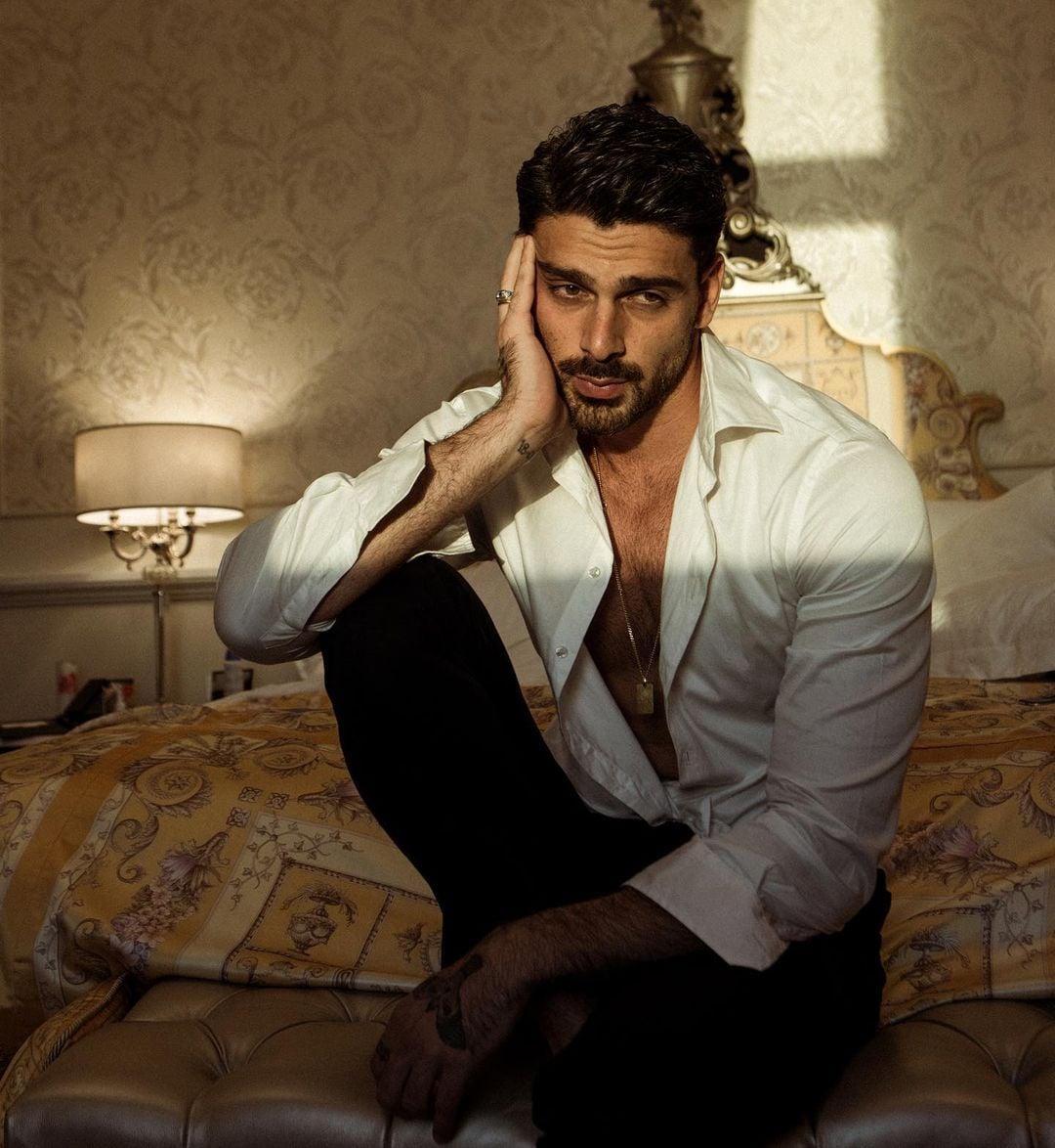 Black-and-white party photo of a smiling man in a check blazer among a crowd.