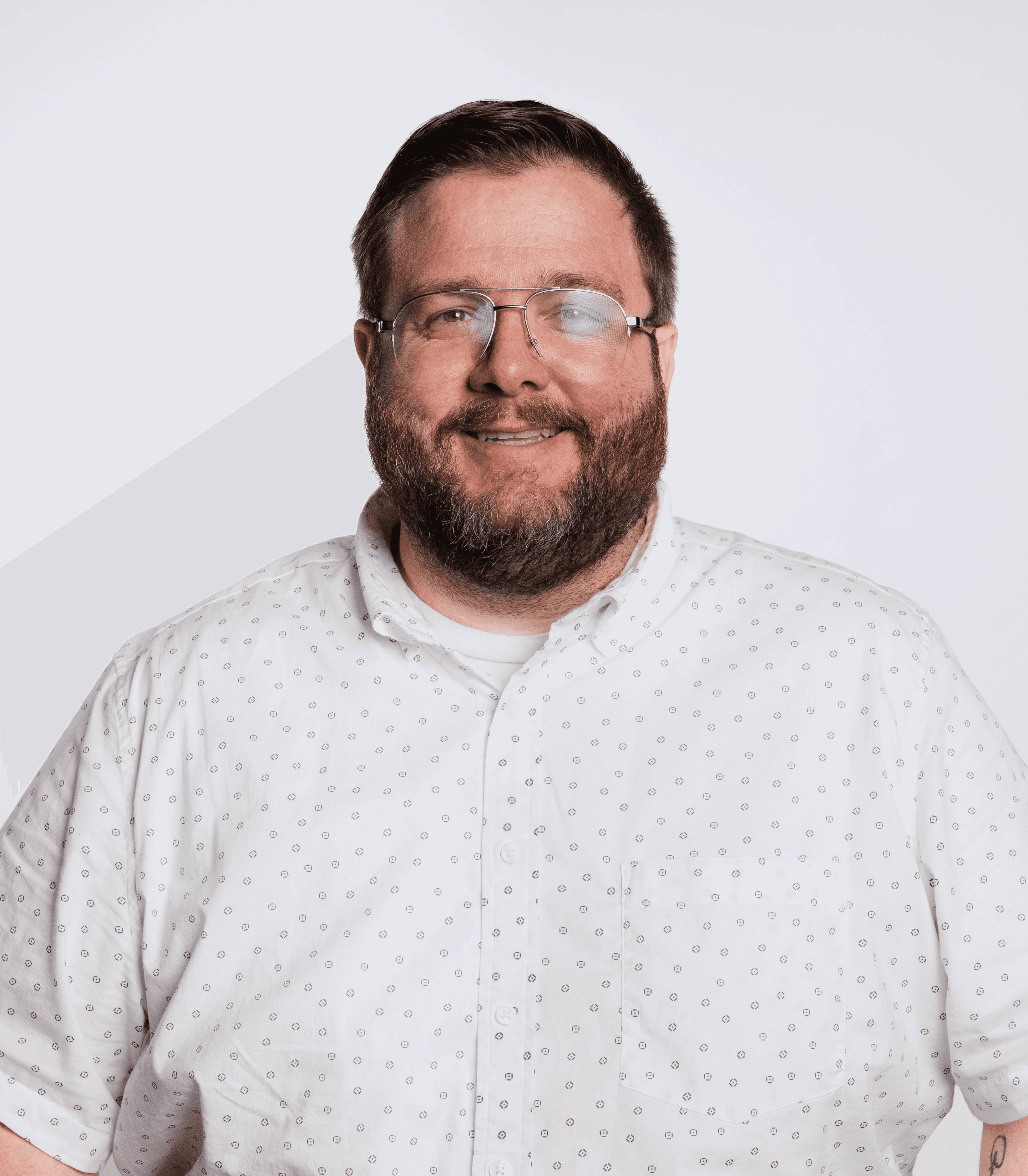 A man smiles and engages with two customers at a countertop in a modern cafe, with a honeycomb-patterned wall behind them.