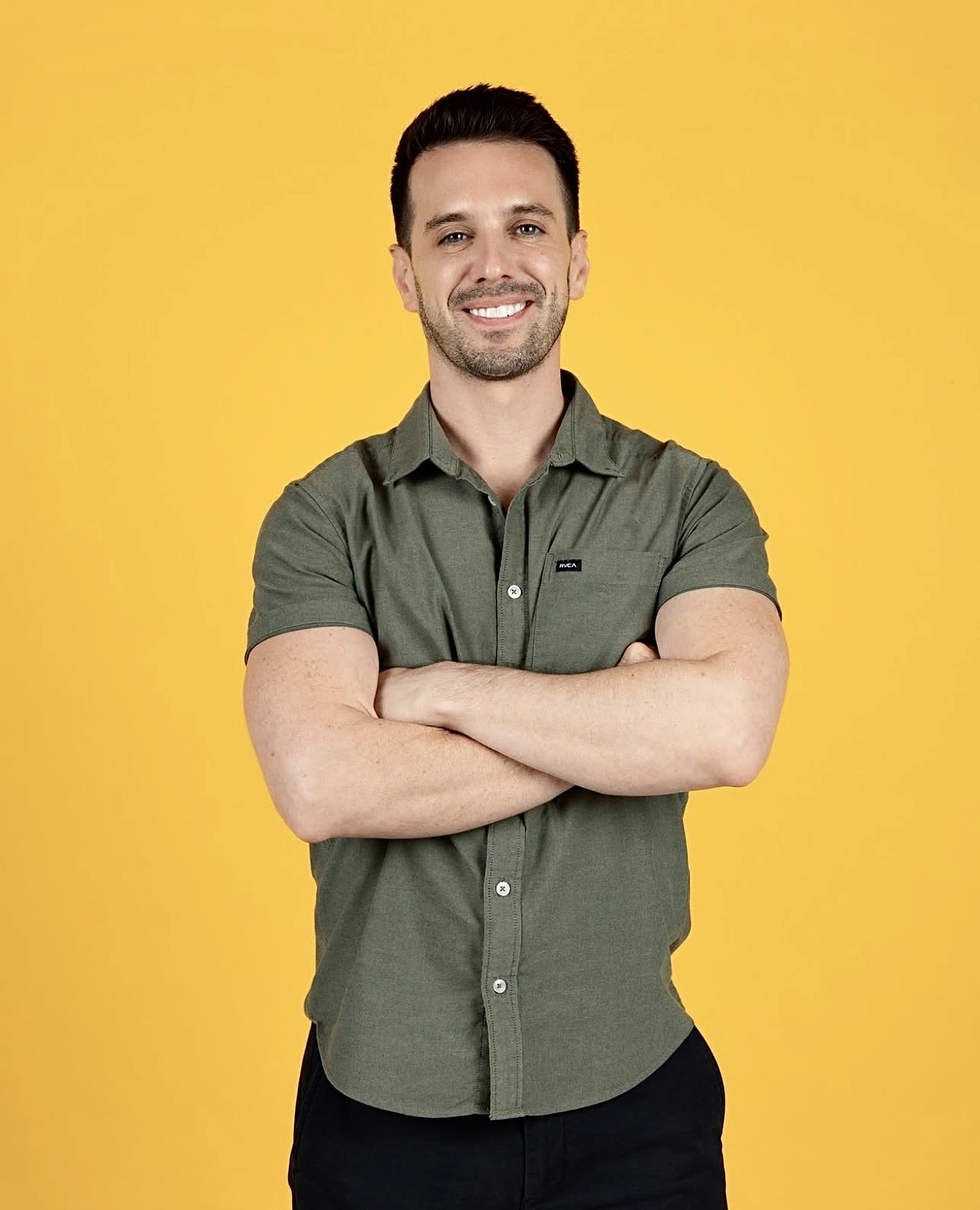 Adam standing confidently with folded arms, dressed casually