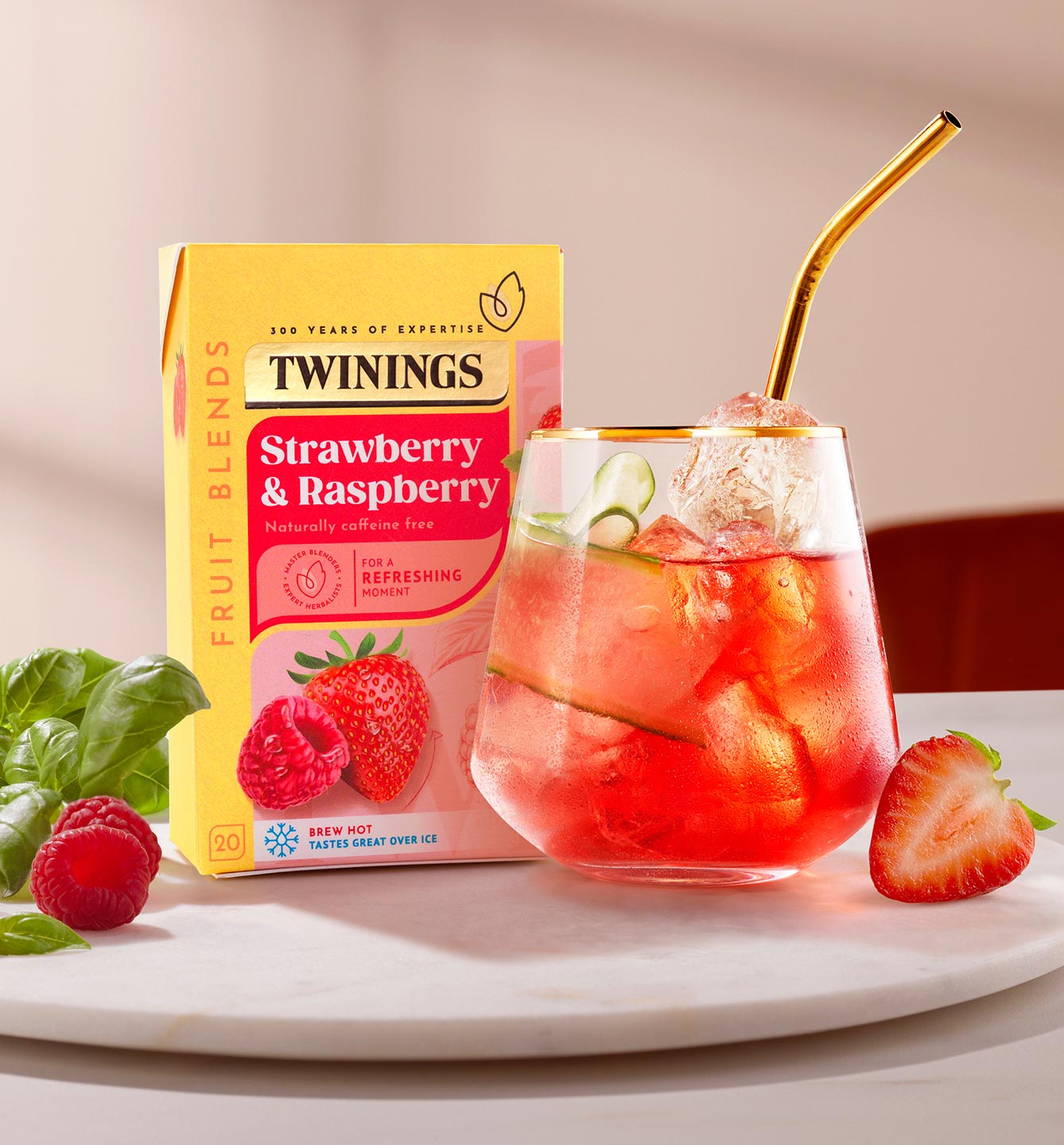 Box of Twinings Strawberry and Raspberry Tea next to a glass with ice and tea in it.