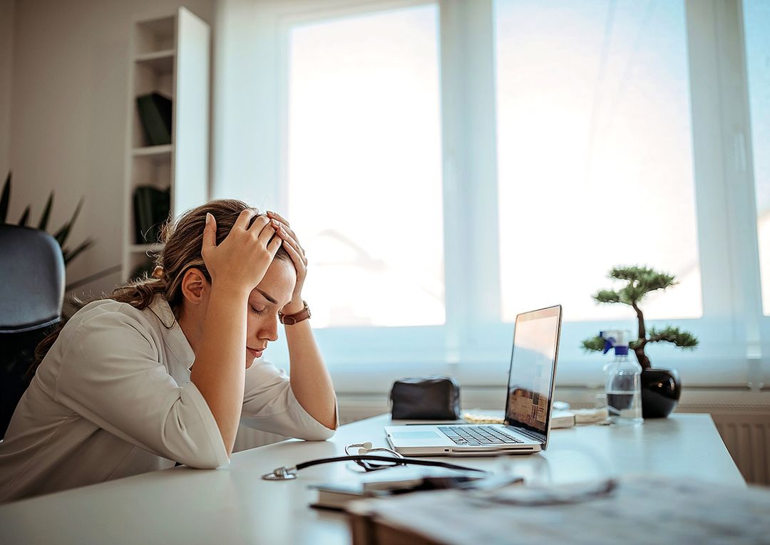 Dental practice owner looking overwhelmed while reviewing staff schedules/payroll at desk