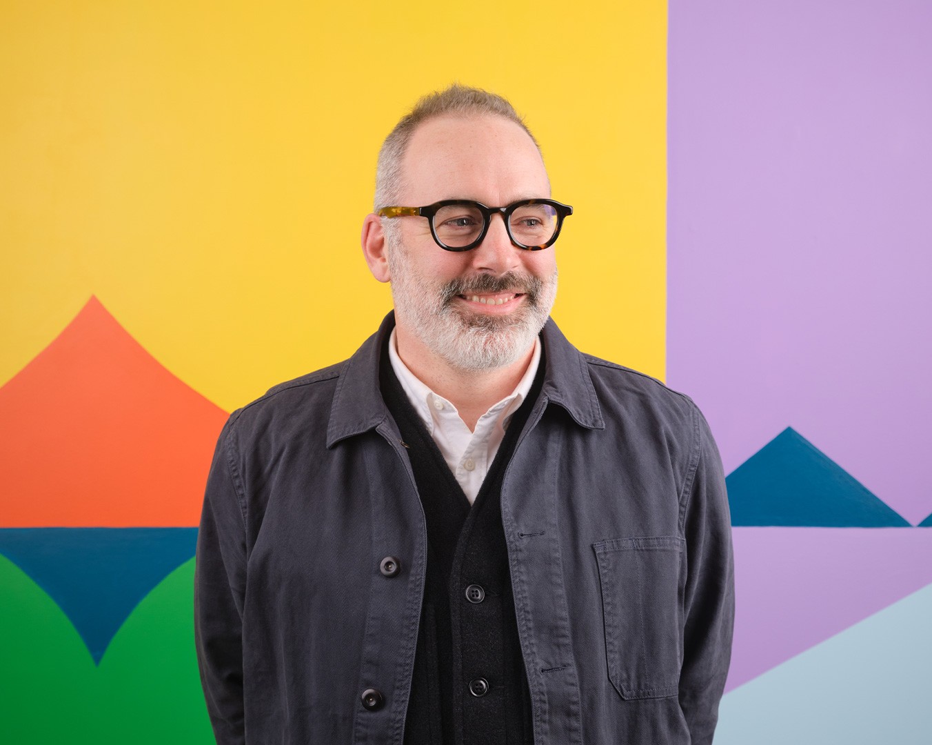 Portrait of Paddy Harrington standing in front of a colourful mural
