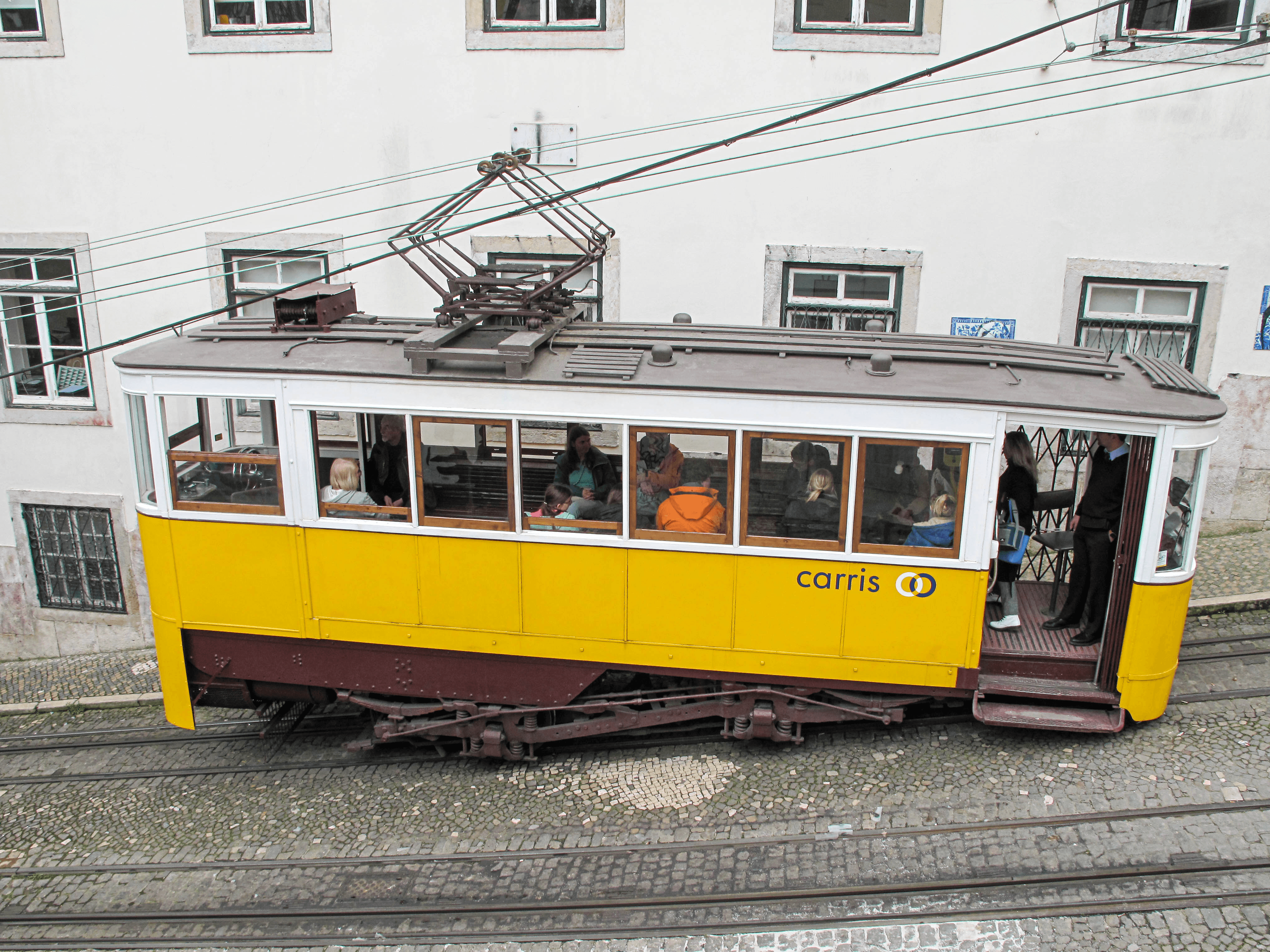 Yellow Ascensor da Glória funicular carrying passengers in Lisbon