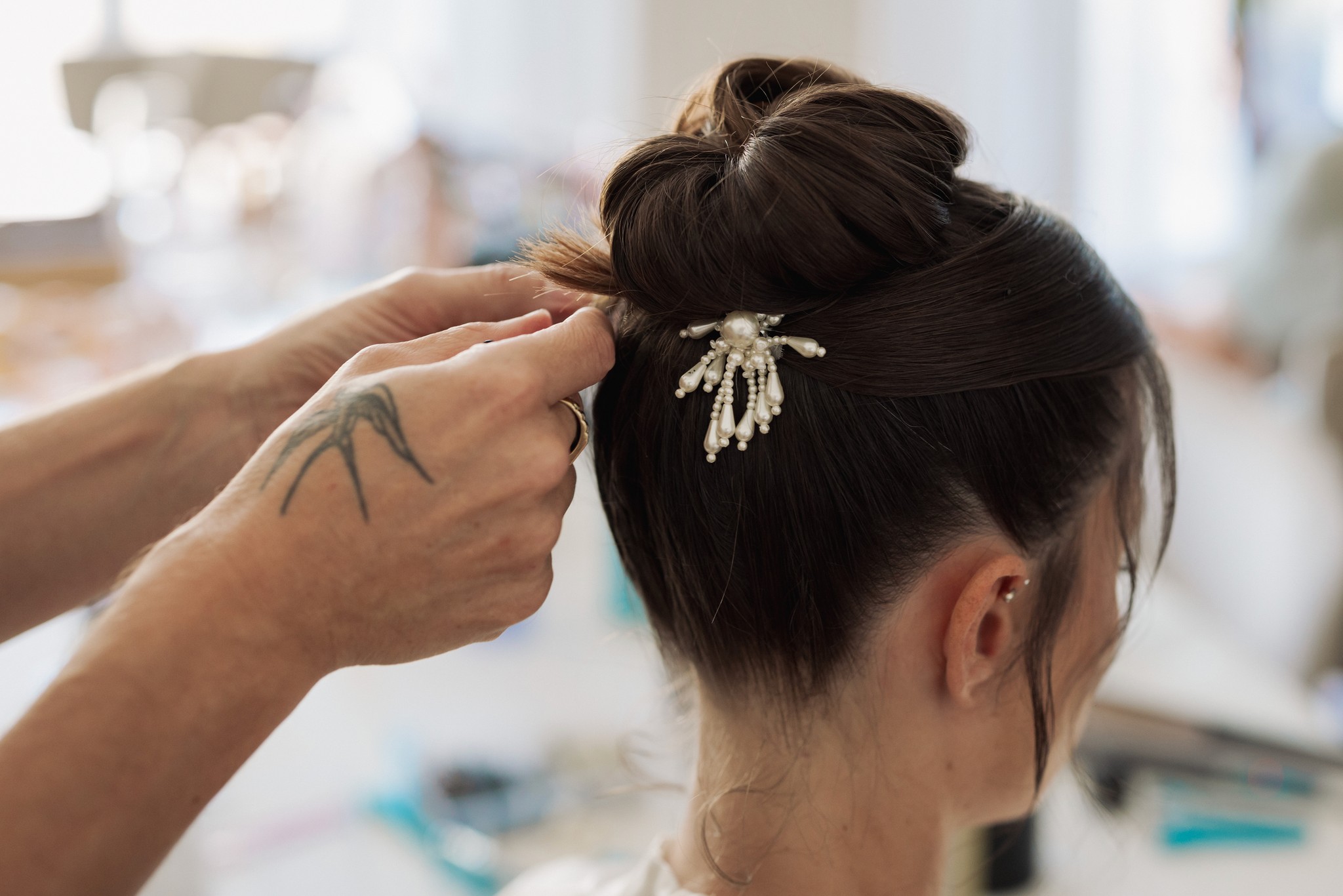 Preparativi della sposa, dettaglio dell'acconciatura con fermaglio ornamentale tra le mani della parrucchiera