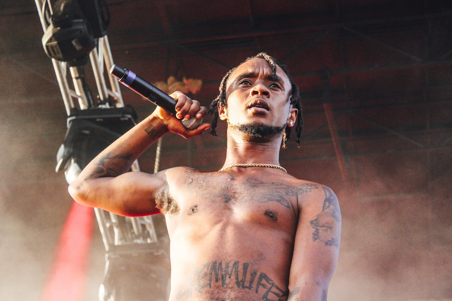 A close-up of a person wearing green-tinted glasses, with a serious expression and smooth skin.