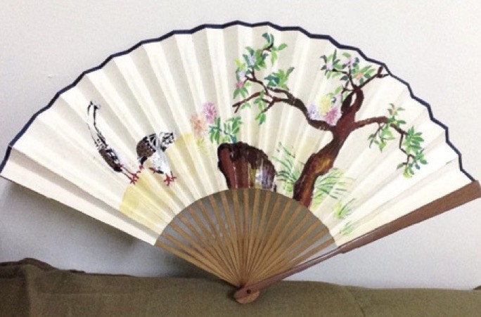 A paper folding fan painted with a tree and a bird