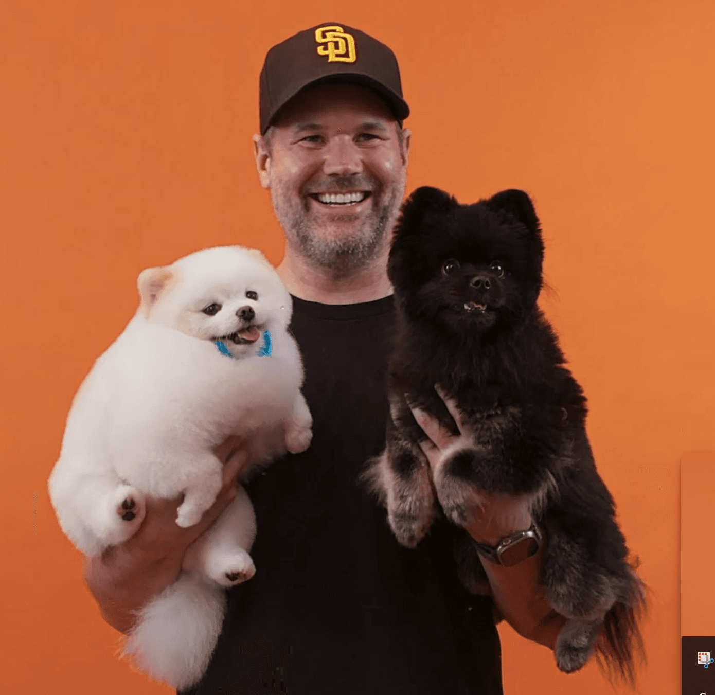 Joyful man holding two fluffy dogs and smiling to convey fun energy, love, and trust in grooming services.
