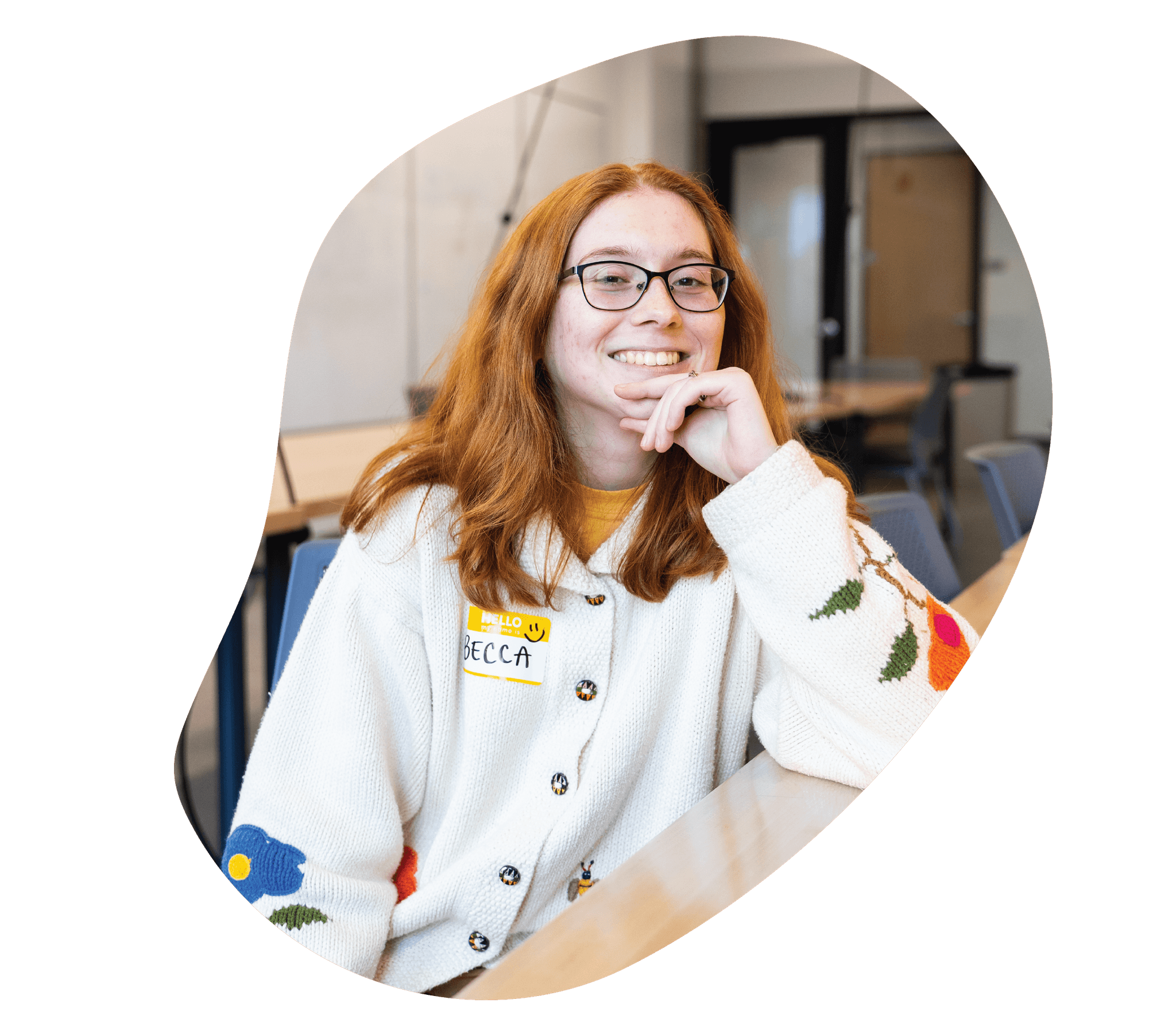 Rebecca Dugan is smiling, wearing a creme and floral cardigan.