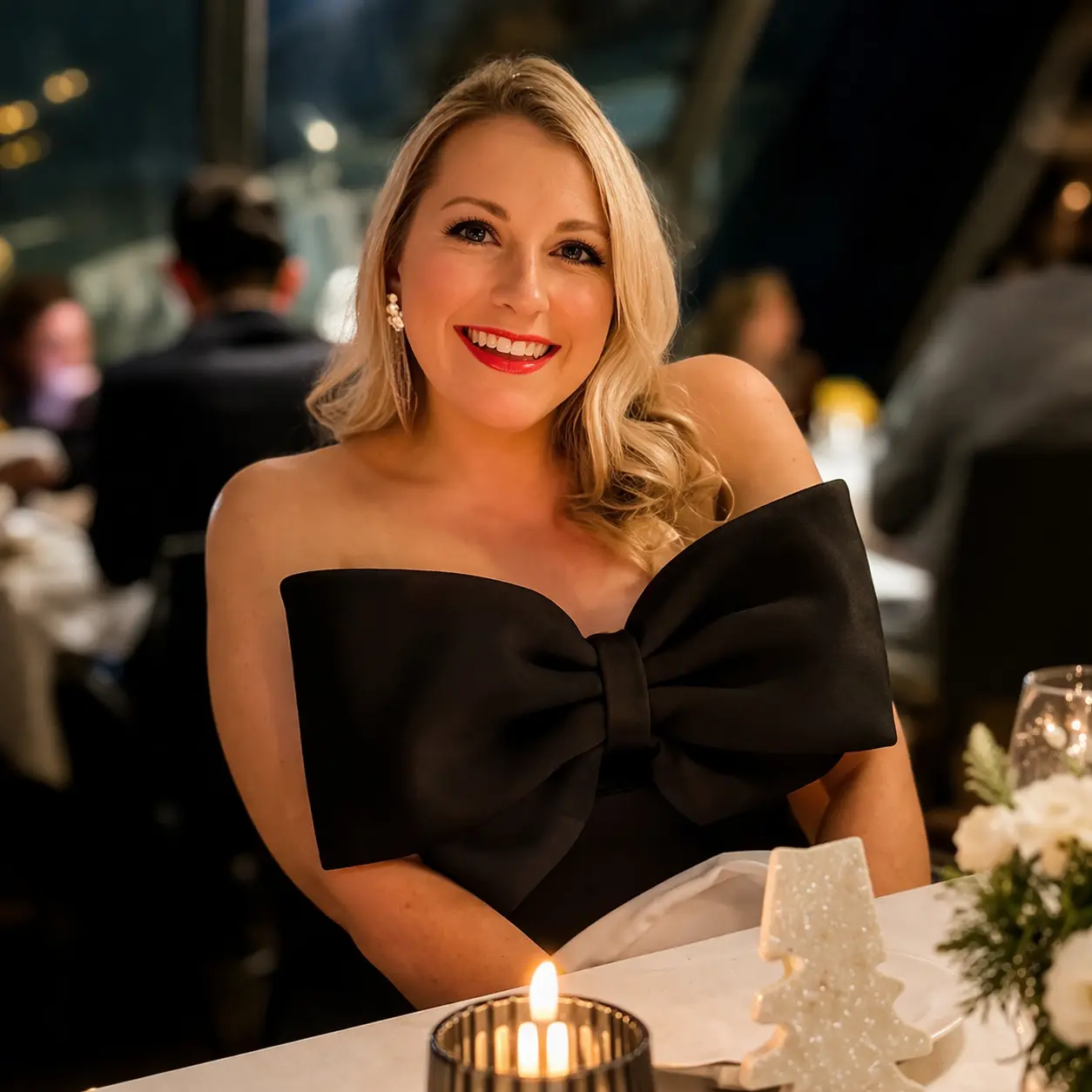 Mollie Y smiling at a candlelit dinner, wearing a black dress in a restaurant setting.