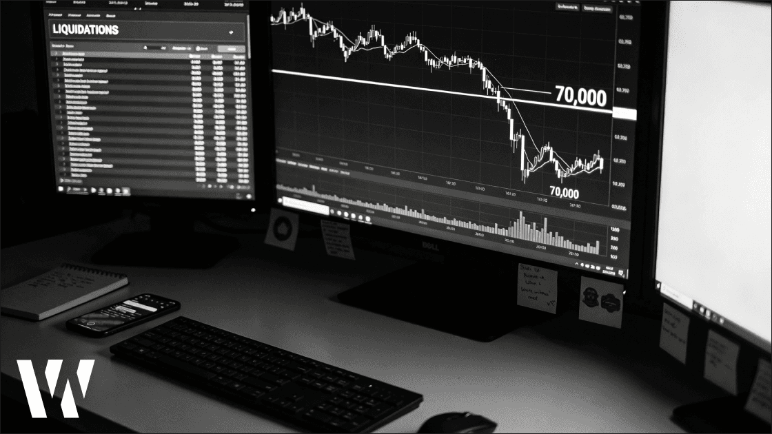 Bitcoin price plunges toward the $70,000 support level on a black-and-white trading desk, with multiple monitors showing a sharp BTC/USD selloff and a “LIQUIDATIONS” panel, capturing a tech-driven risk-off move and forced deleveraging in crypto markets.