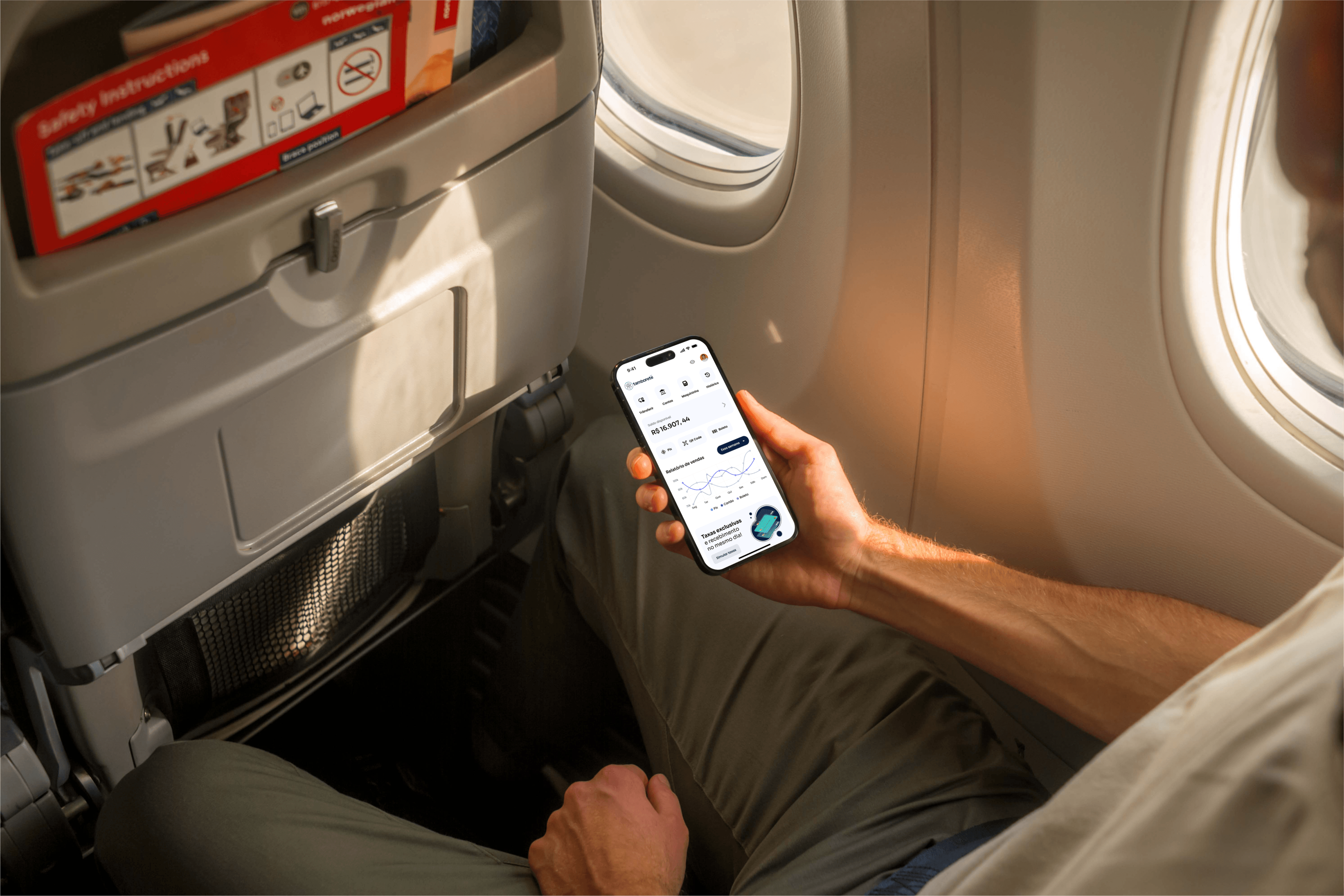 imagem mostrando um homem sentando na cadeira de um avião com o aplicartivo do banco aberto e olhando seu faturamento