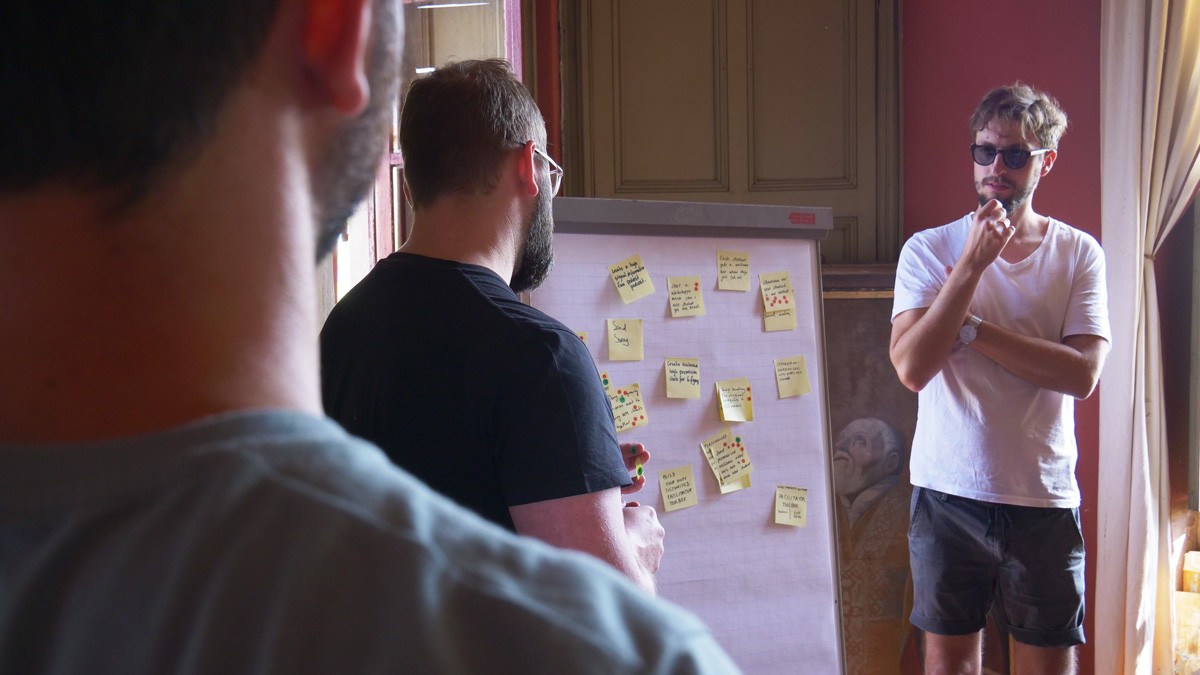 Team reviewing sticky notes with ideas on a flipchart board during a company retreat workshop