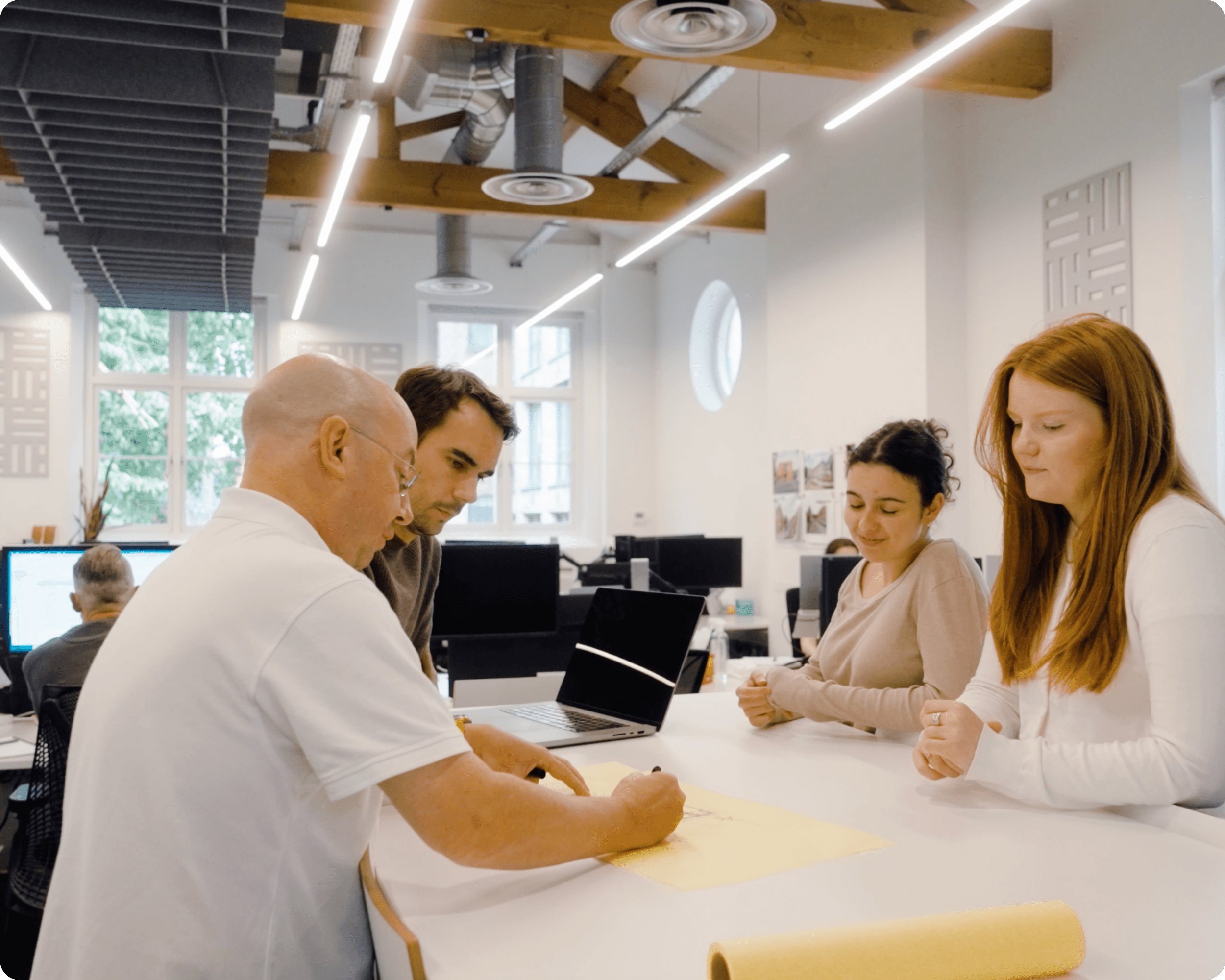 Architecture team collaborating around project drawings in a bright studio.
