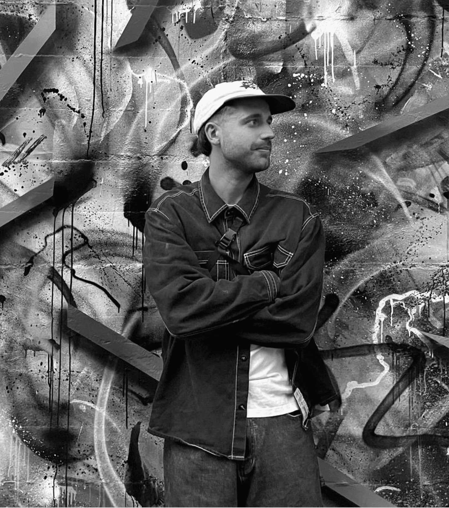 A thoughtful young person with dark hair gazes to the side, captured in soft black and white lighting.