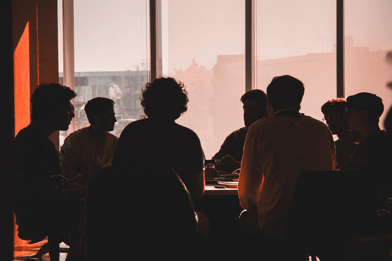 Group of people silhouetted in a meeting around a table, discussing ideas.