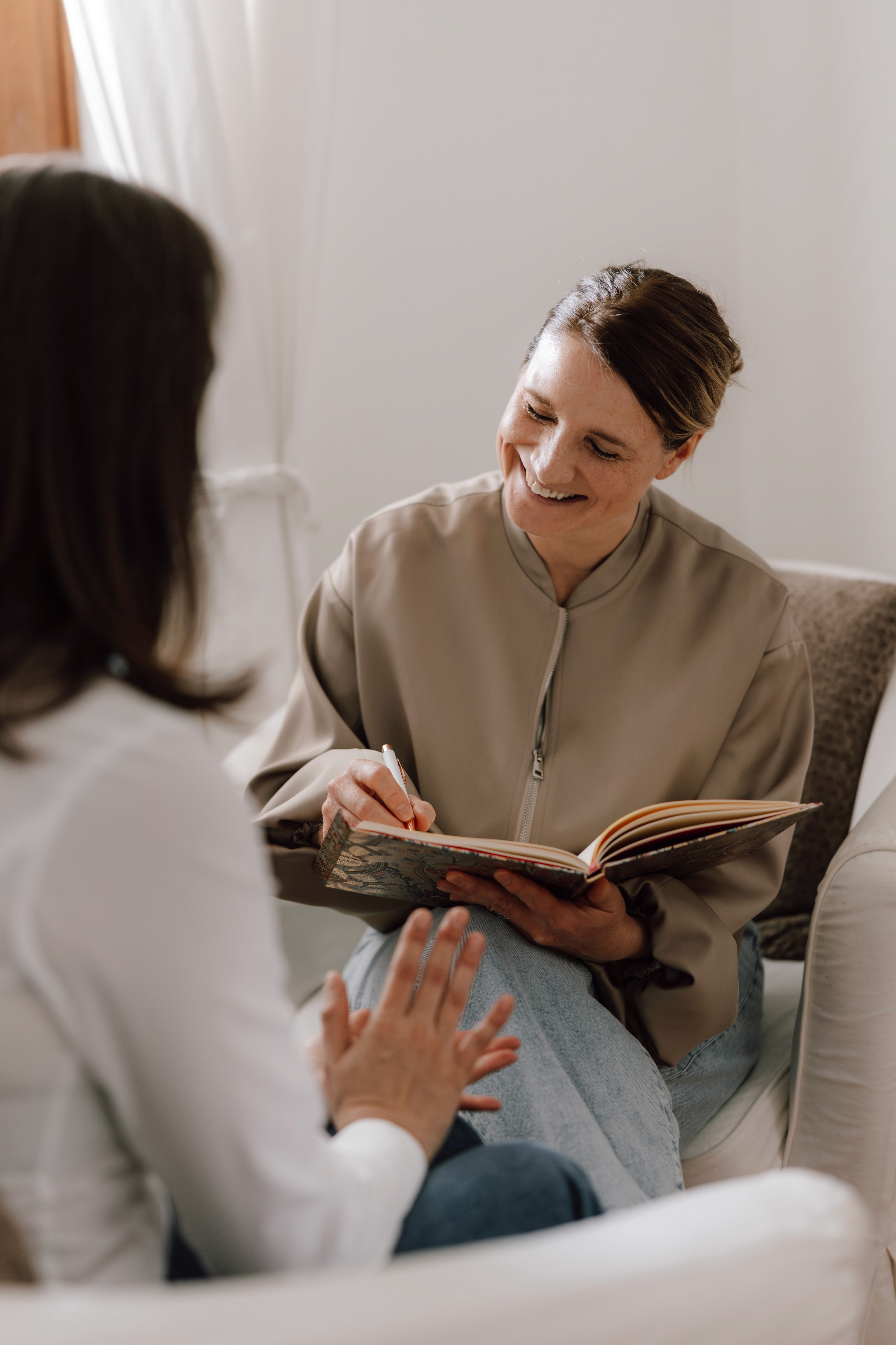 A person with curly hair sits at a desk, working on a laptop in a cozy, well-lit environment.