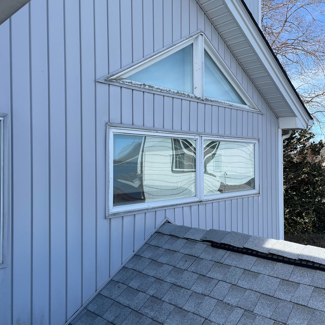 Triangle and picture windows in vertical siding above shingle roof
