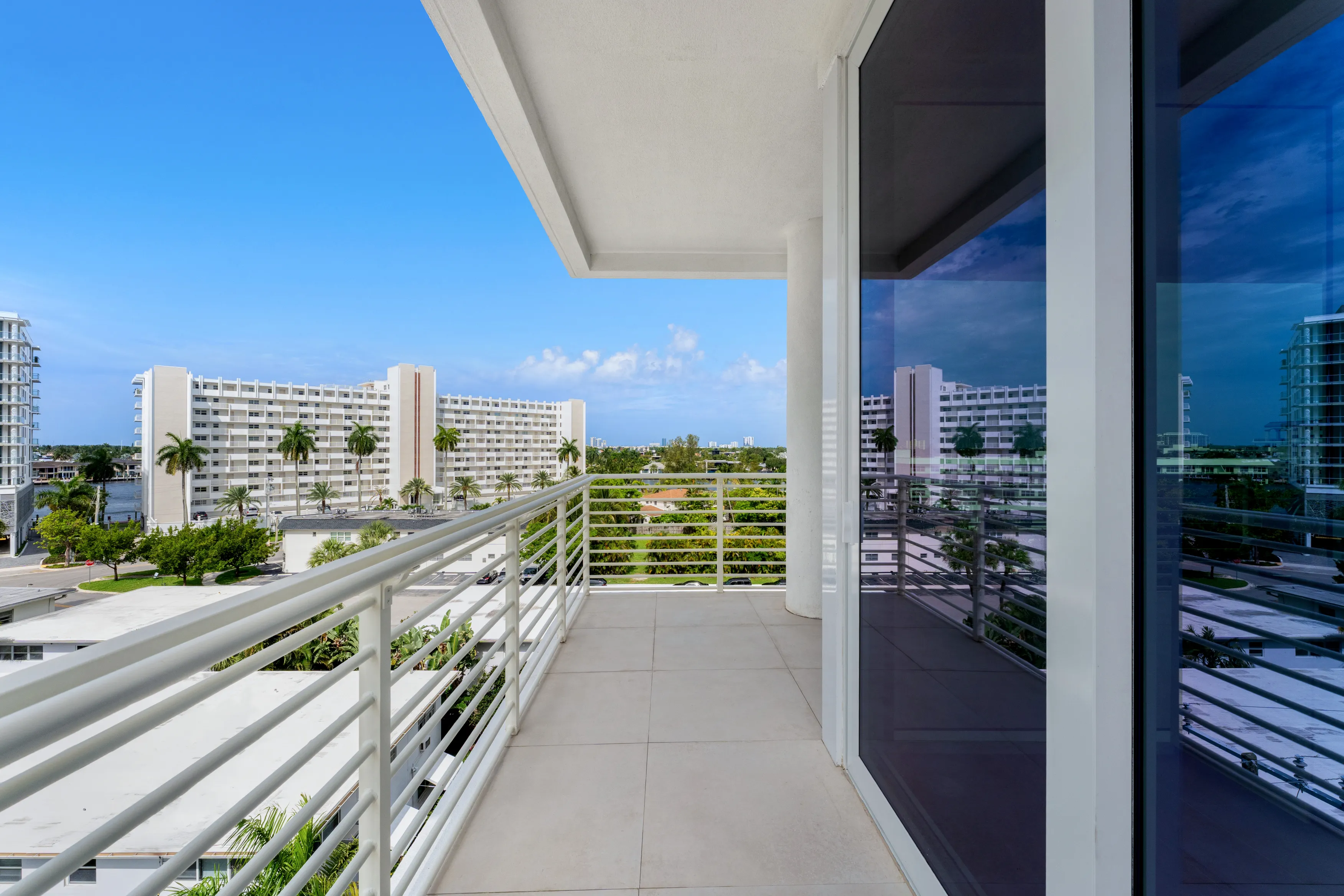 A balcony featuring wicker furniture overlooks a serene ocean view under a clear blue sky.