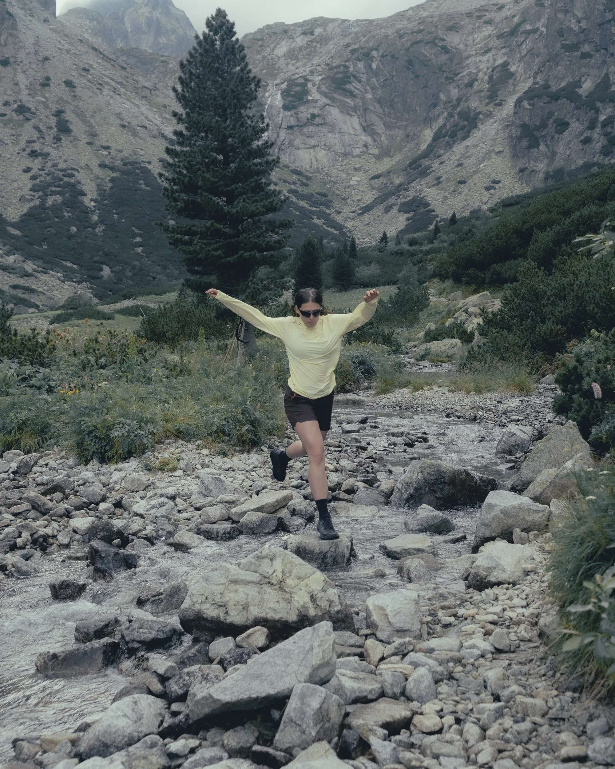 picture of a running woman in mountains, hopping over river.