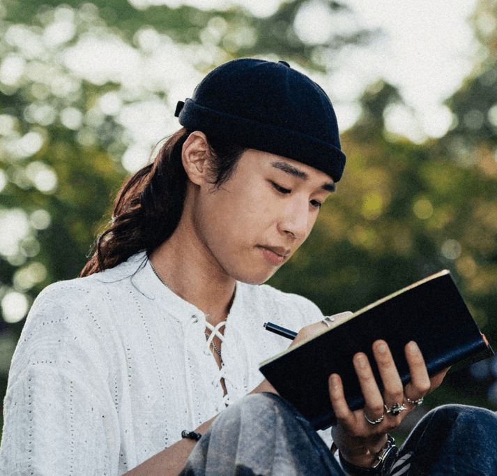 A smiling man with short hair stands with arms crossed, wearing a dark shirt against a neutral background. (Background Removed)