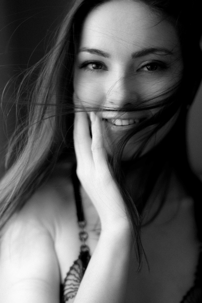 Smiling woman in elegant boudoir pose, celebrating self-love and art in Switzerland.