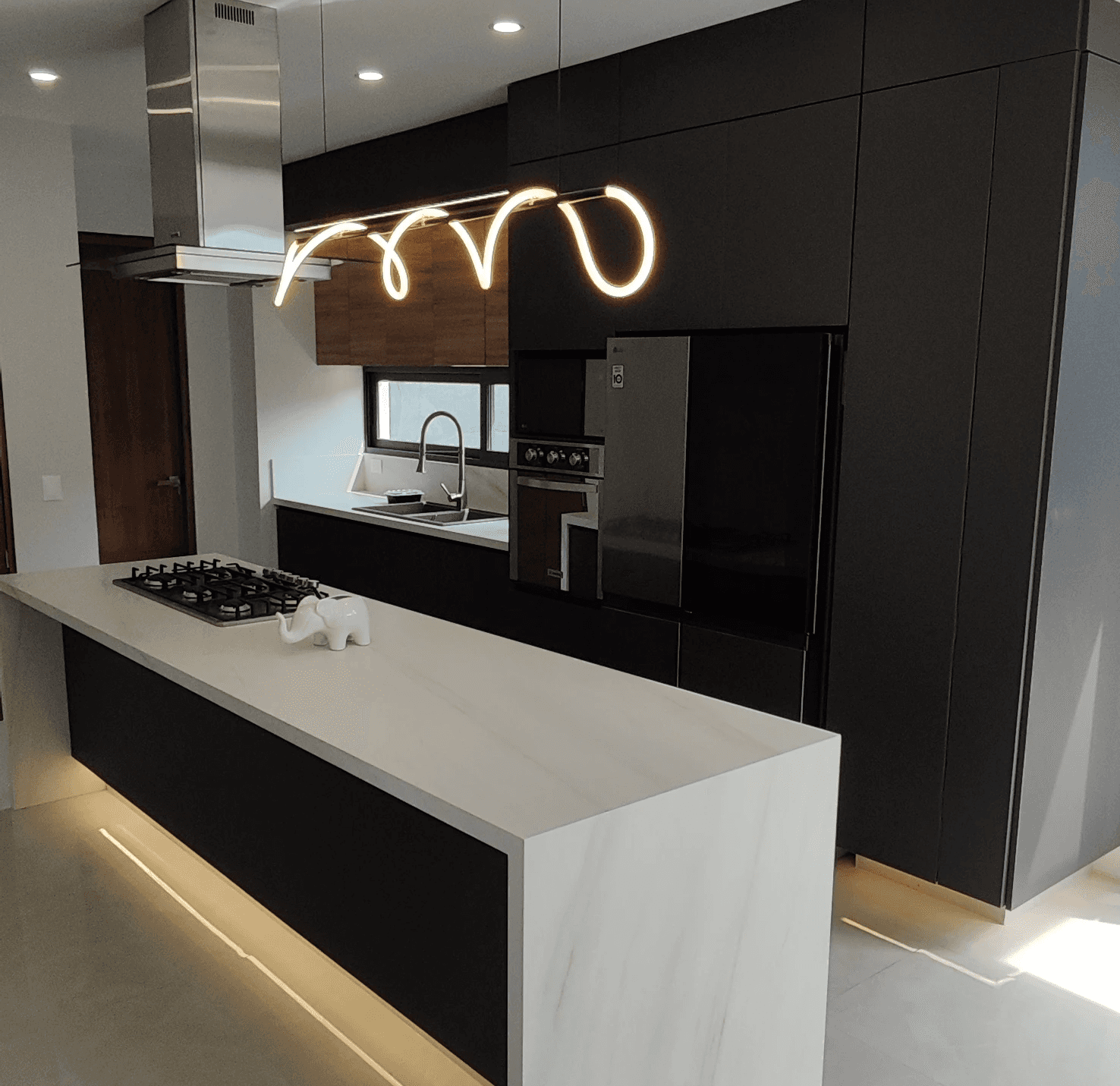 Modern indoor space with large glass doors, lush greenery, and a cozy seating area visible beyond.