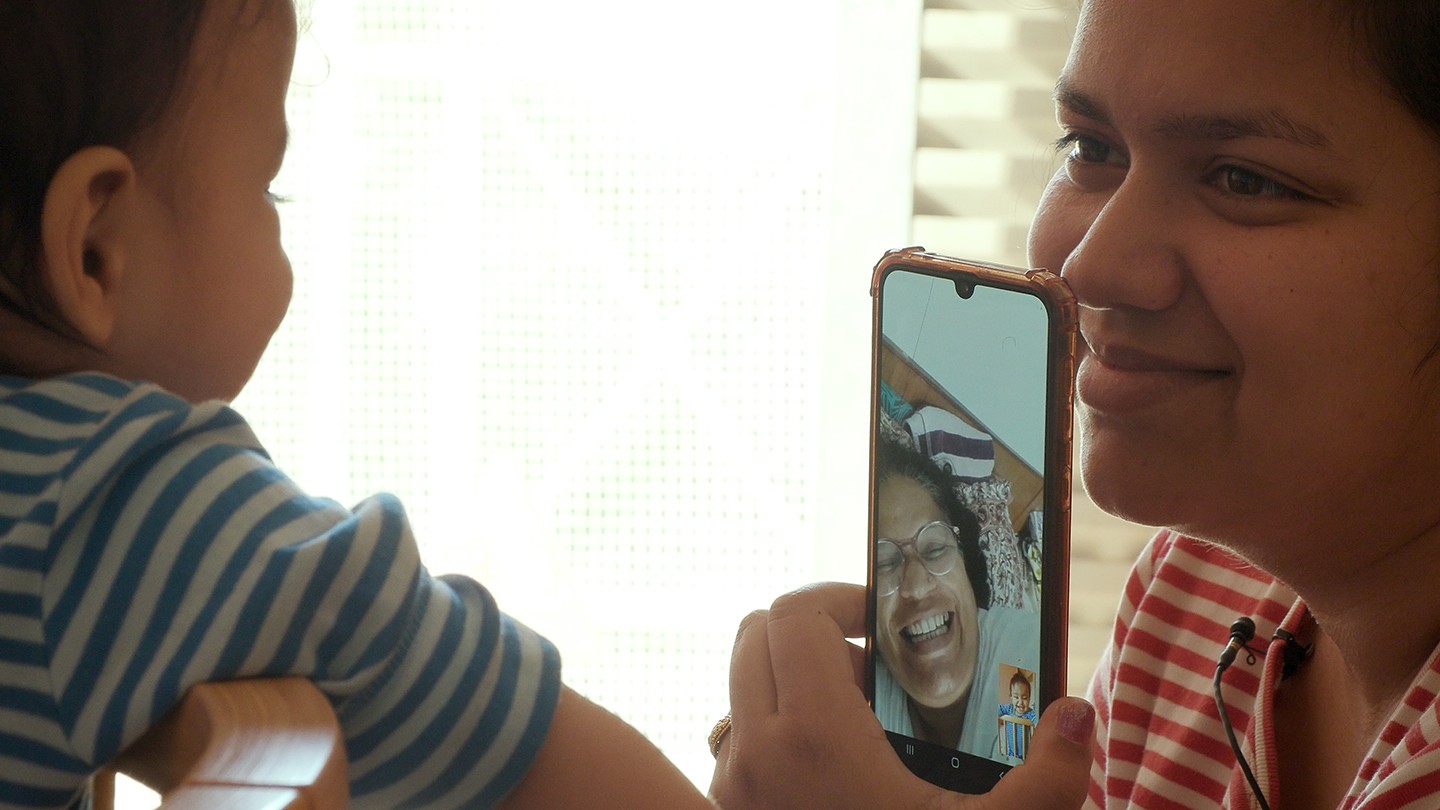 Μητέρα και παιδί κάνουν βιντεοκλήση με μέλος της οικογένειας, μοιράζοντας μια στιγμή σύνδεσης.
