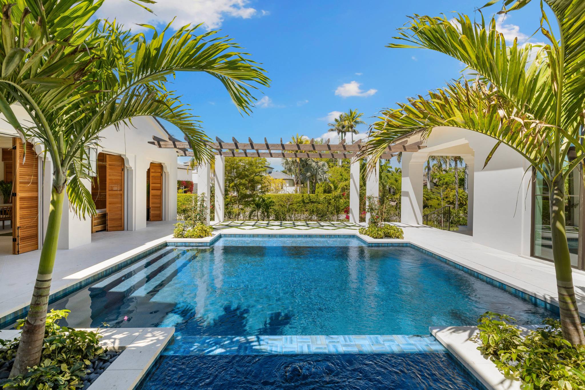 a luxury pool surrounded by white modern architecture and palm trees