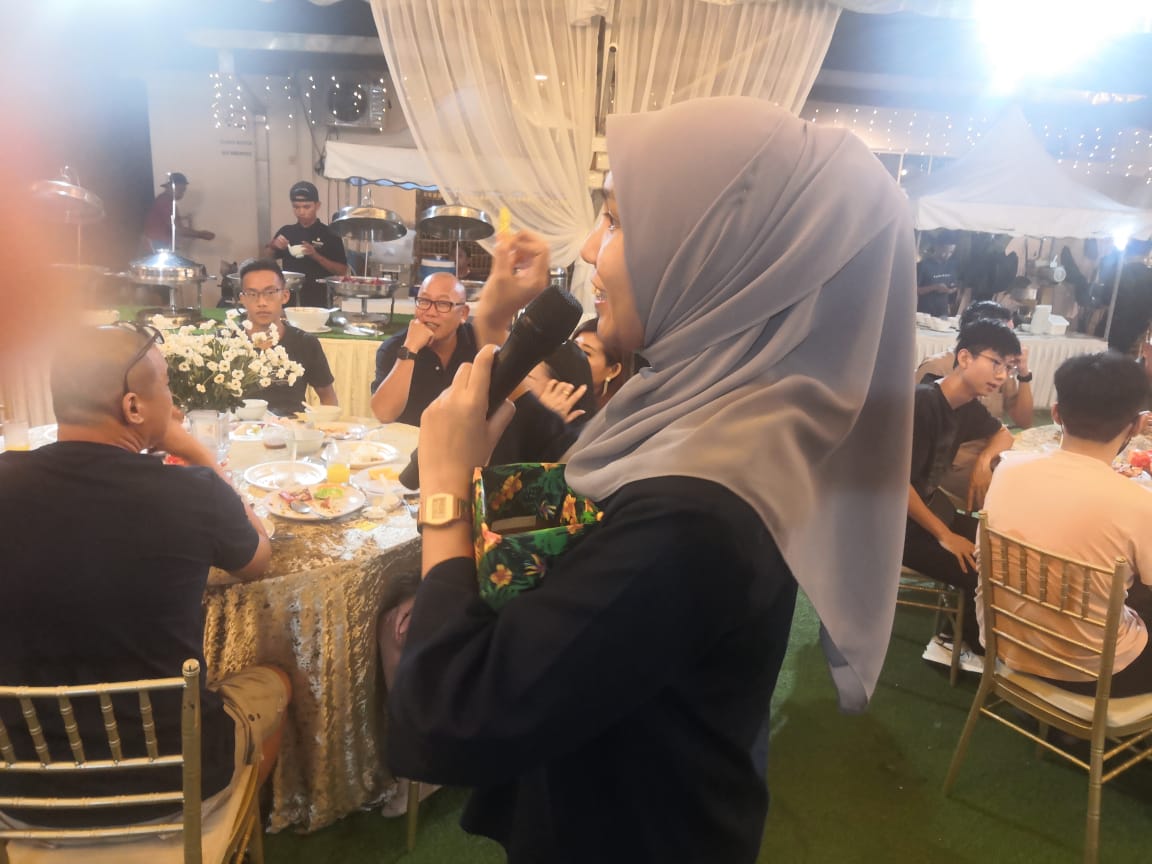 Female employee speaking into a microphone during the Annual Dinner 2023 program or prize draw.