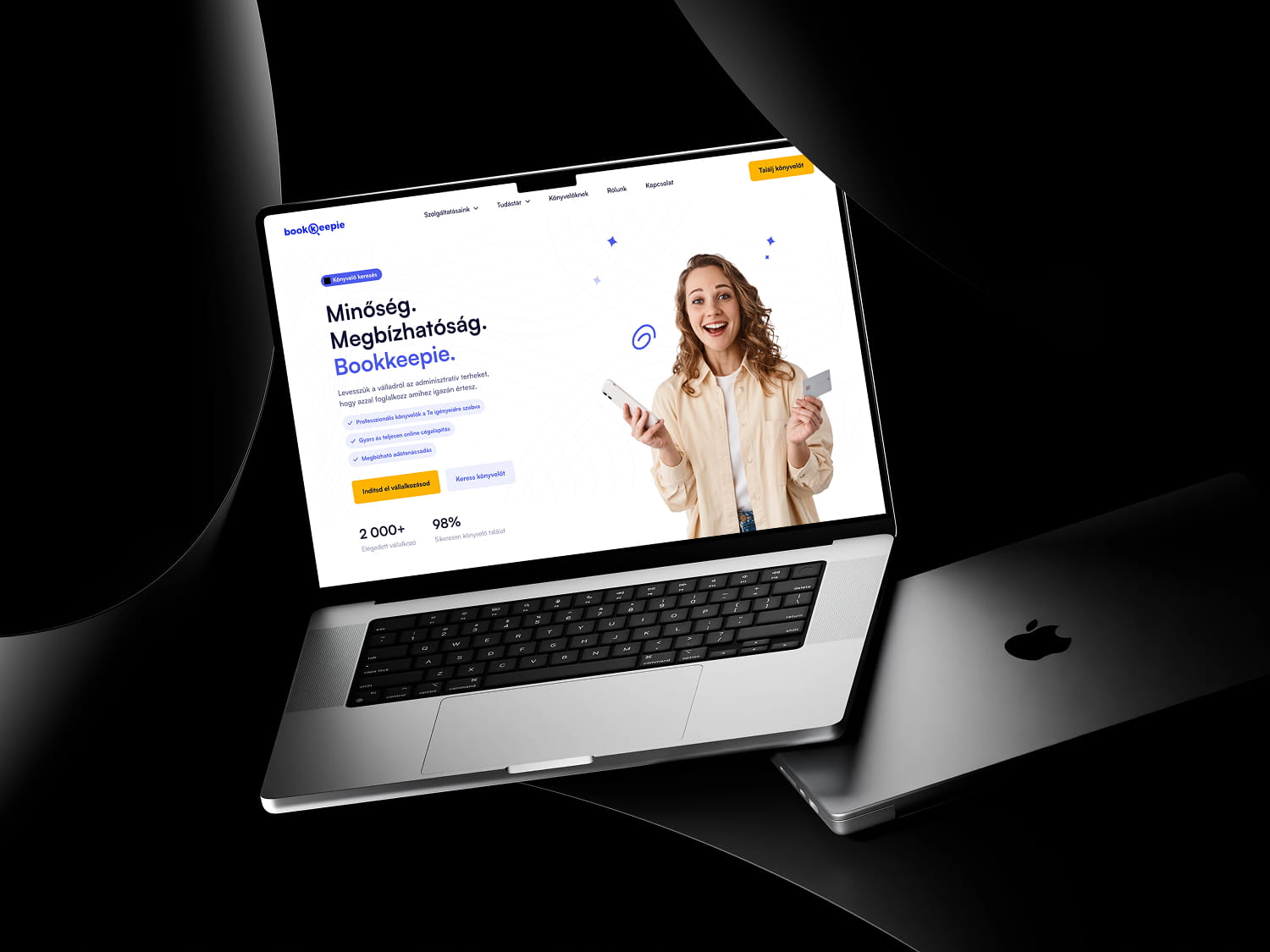 Bookkeepie website on a laptop, woman holding cards.