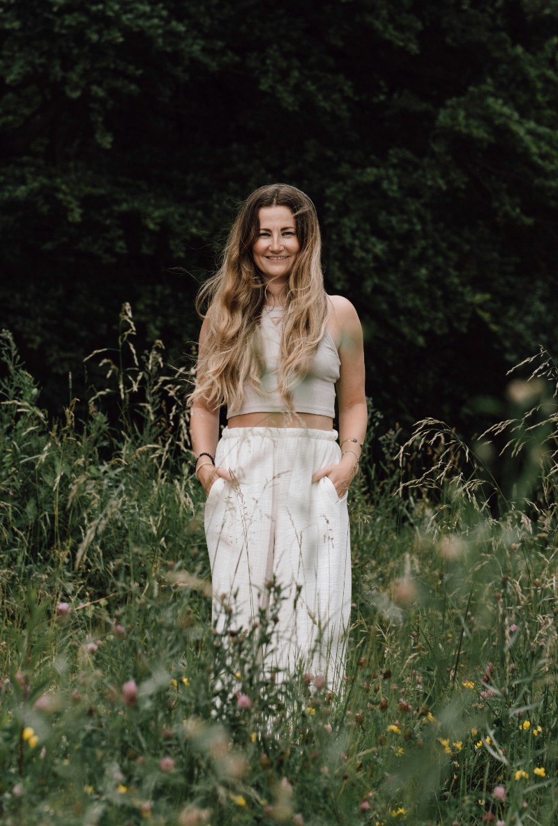 Antonia steht lächelnd inmitten einer grünen Wiese