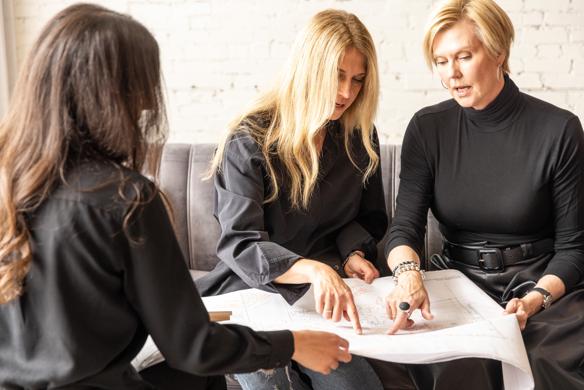 Image of Women in black discussing home design and layout with architectural plans, focusing on interior design construction.