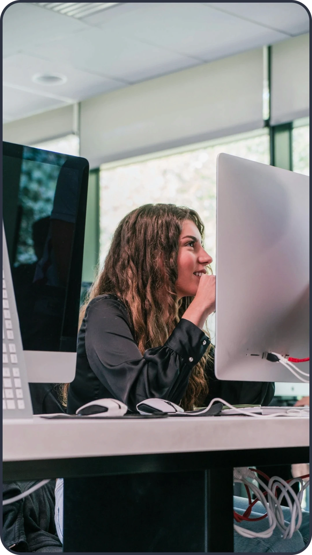 Woman working at a desktop computer with payroll cards showing funded amount, balance, and the next pay cycle.
