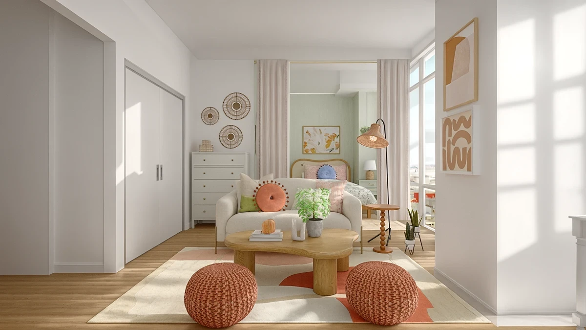Studio living room with a white sofa, coral knit poufs, and a wood coffee table, with a curtained-off bedroom entrance behind it.