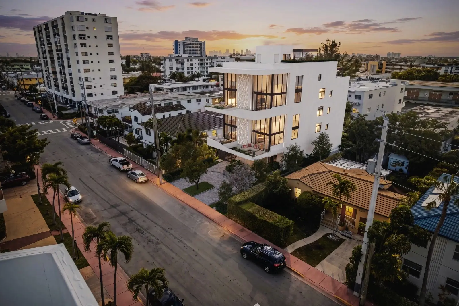 Aerial view of Byron Avenue Residence in South Beach, Miami Beach, at sunset, with palm lined streets and the city skyline in the distance