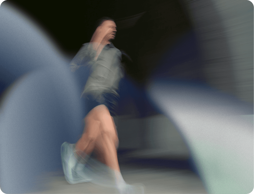 A winding road cuts through rocky terrain, surrounded by patches of green grass and illuminated by sunlight.