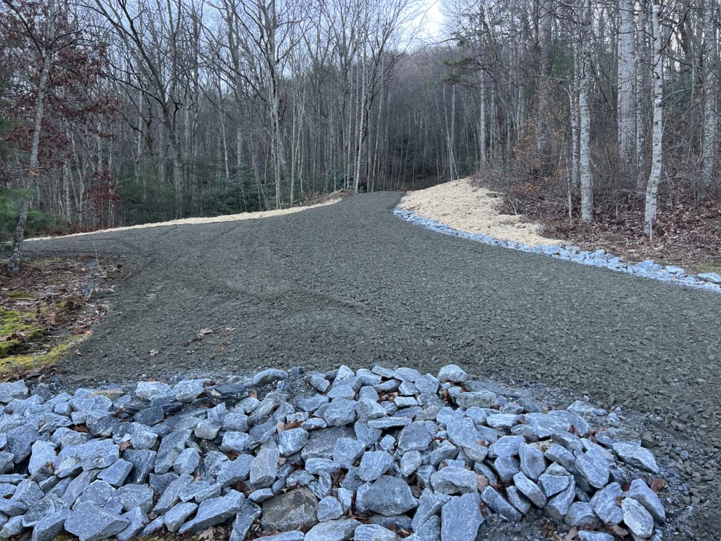 Freshly constructed gravel driveway with compacted base and clean drainage edges in a wooded rural area near Kansas City.