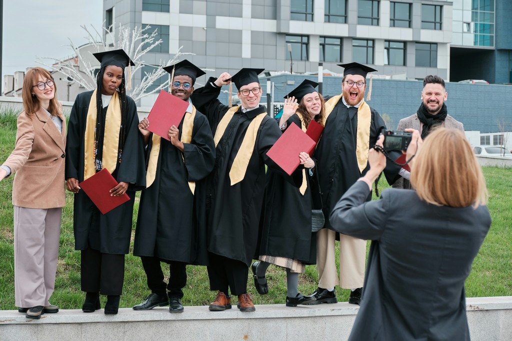 A group of happy graduates in black gowns and gold stoles pose with their diplomas for a celebratory photo, capturing the joy and pride of their academic achievement, surrounded by friends and family.