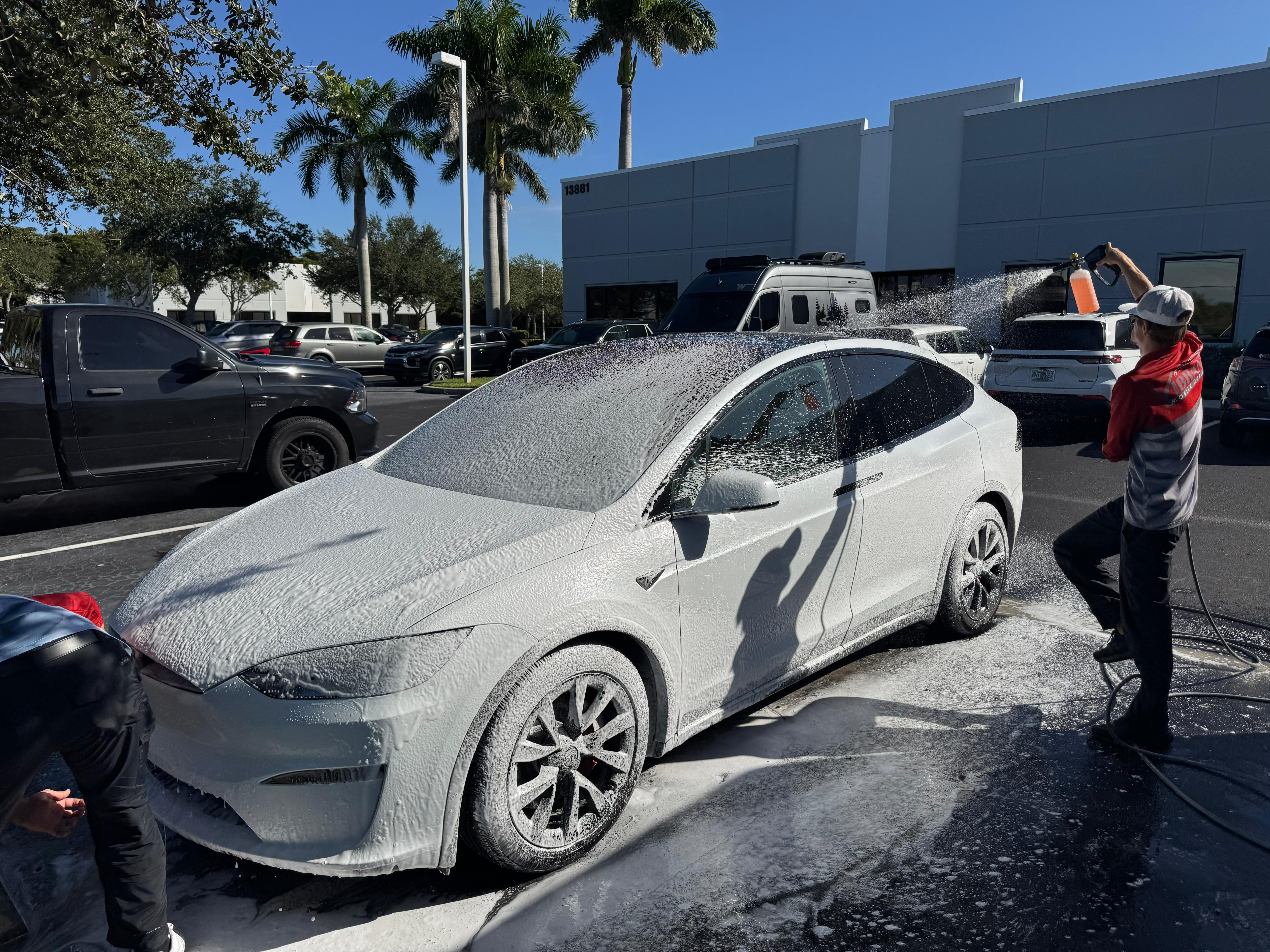 Undercarriage of Tesla Model X with salt and sand buildup before pressure cleaning