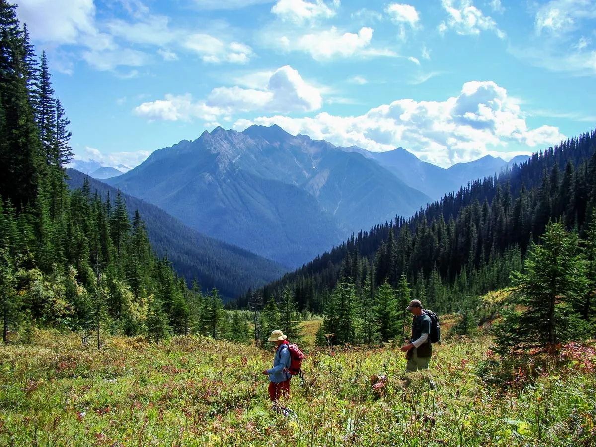 Adventurers explore the backcountry under blue skies and dramatic mountain scenery