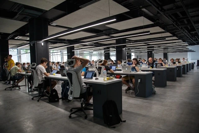 Oficina de espacio abierto con varias personas trabajando en portátiles, la nueva etapa laboral tras terminar los estudios en España