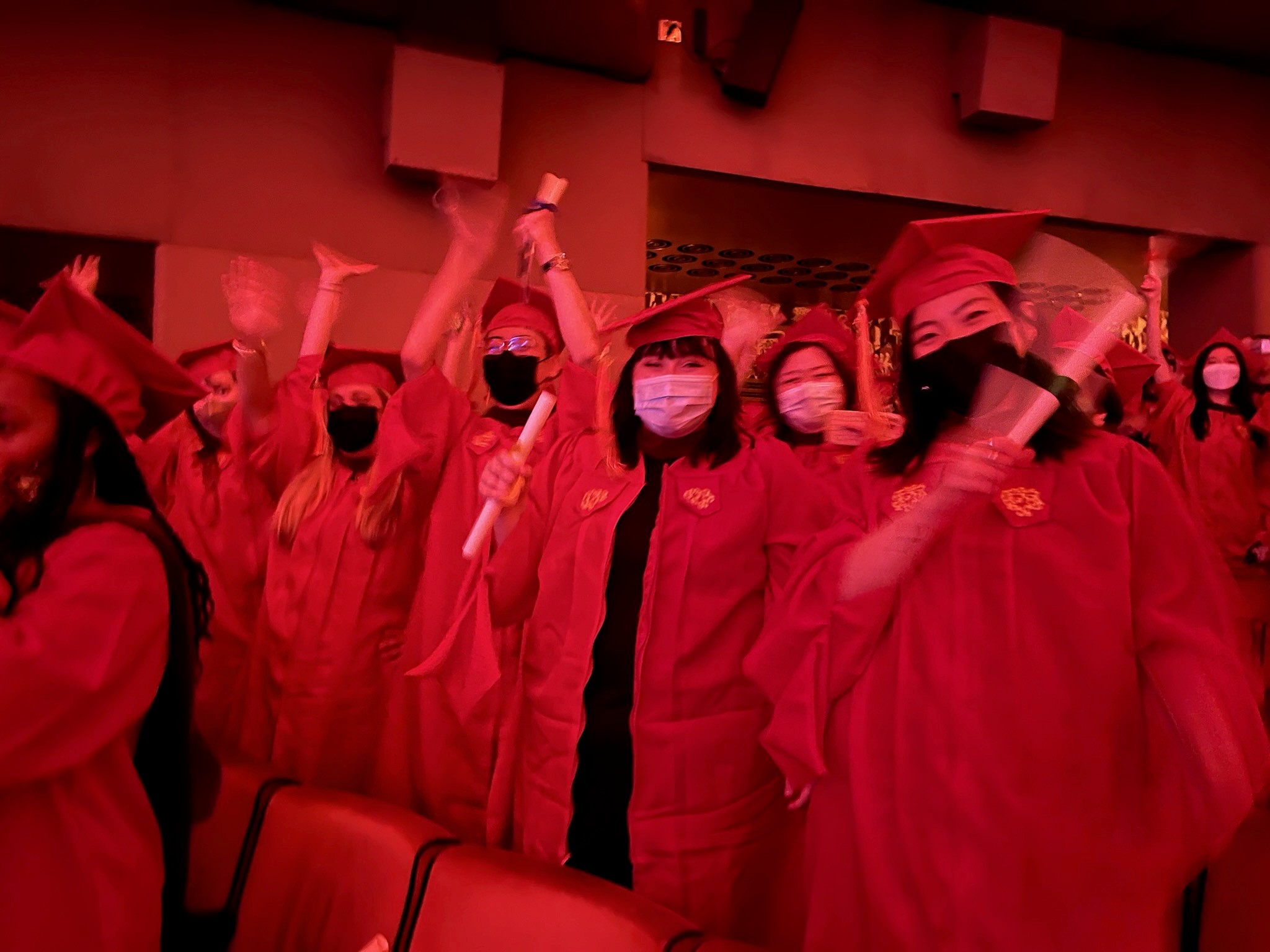 A red filtered photo of a group of grad students sitting in a festive hall.